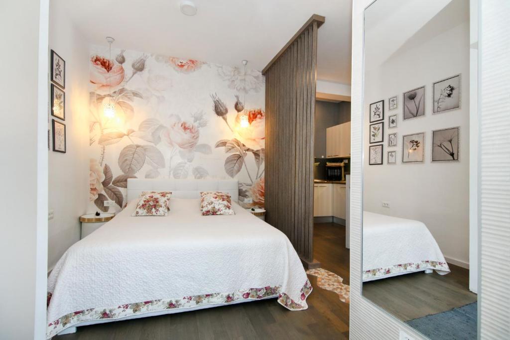 a bedroom with a white bed with flowers on the wall at Anna Apartments in Split