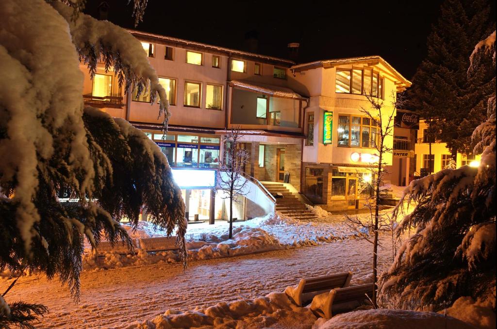 a snow covered street at night with a building at Plaza Family Hotel in Smolyan