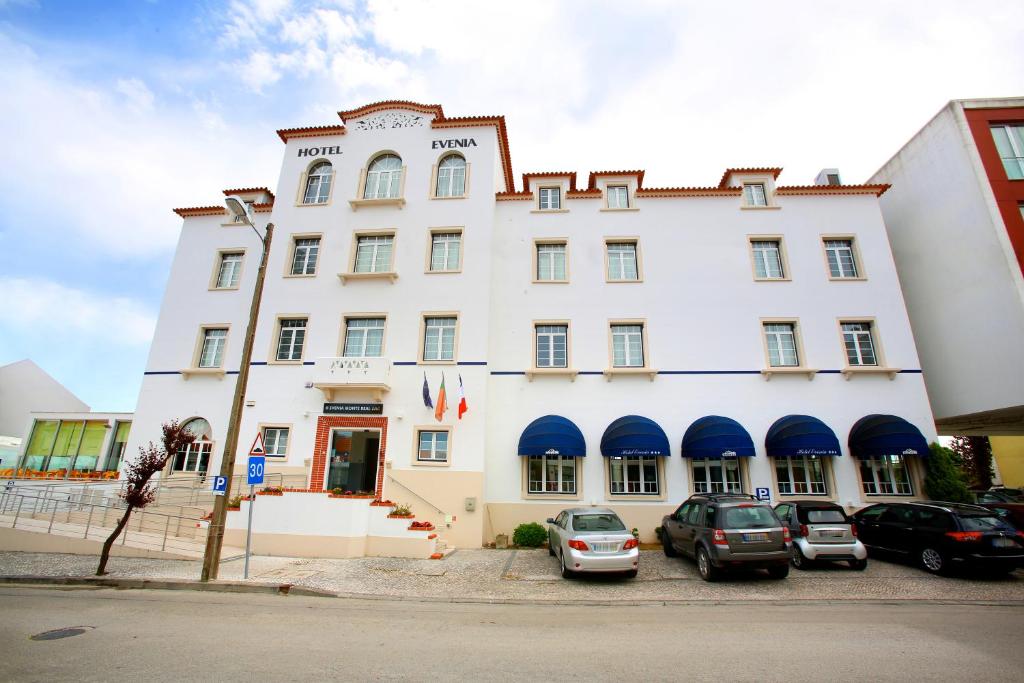 un grande edificio bianco con macchine parcheggiate di fronte di Evenia Monte Real a Monte Real