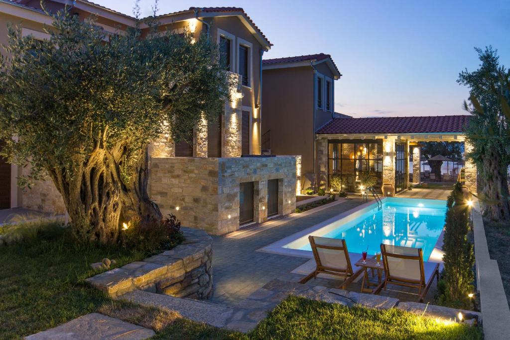 a home with a swimming pool and two chairs and a house at By the sea luxury suites in Limenas