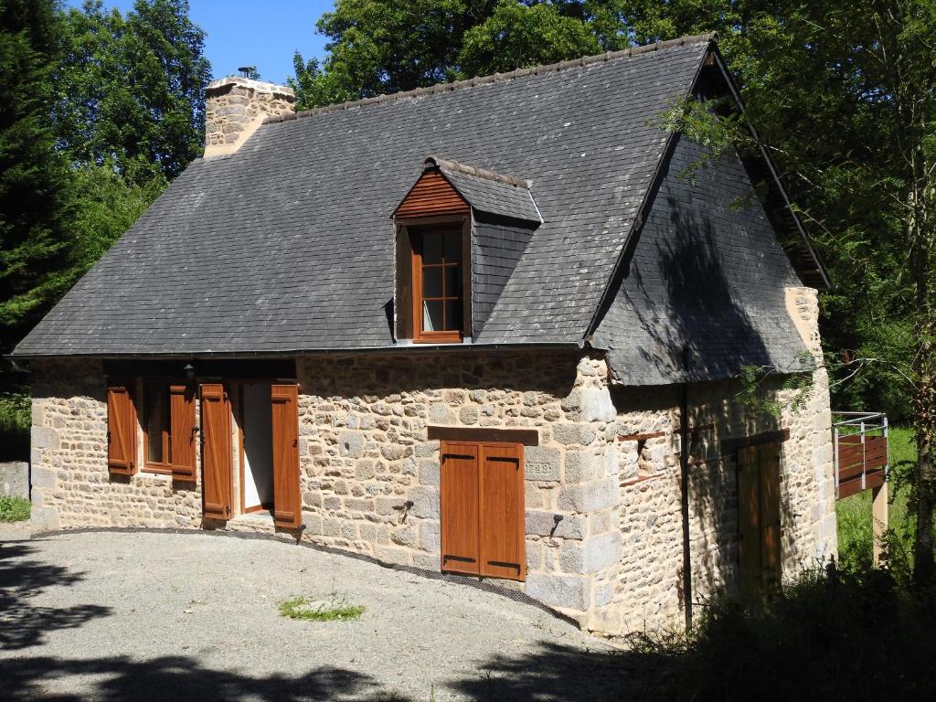 een oud stenen huis met bruine deuren en ramen bij L'Etang in Val Couesnon