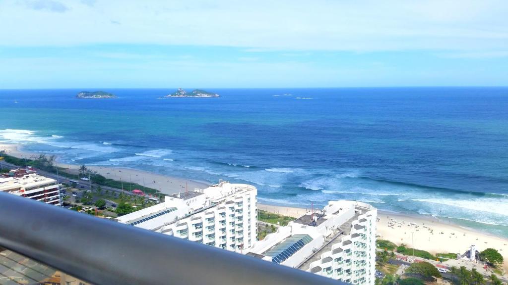 Elle offre une vue sur la plage, les bâtiments et l'océan. dans l'établissement Barramares Flat, à Rio de Janeiro