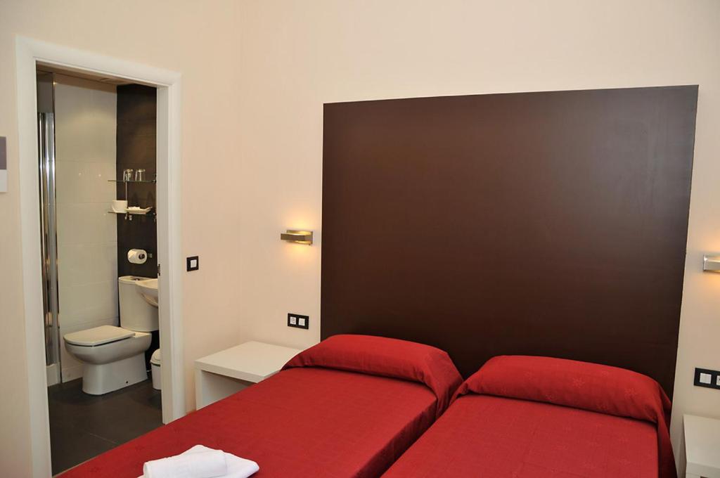 a red bed in a small room with a bathroom at Center Gran Via in Barcelona