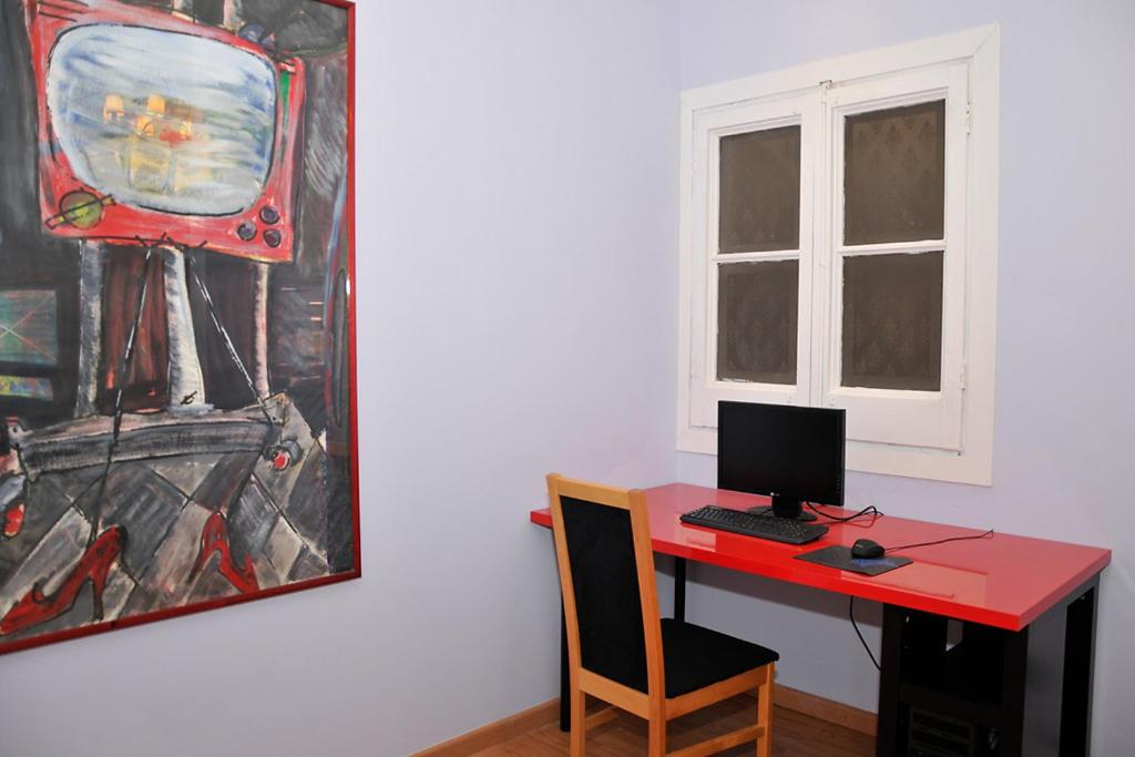 a desk with a computer and a painting on the wall at Center Gran Via in Barcelona