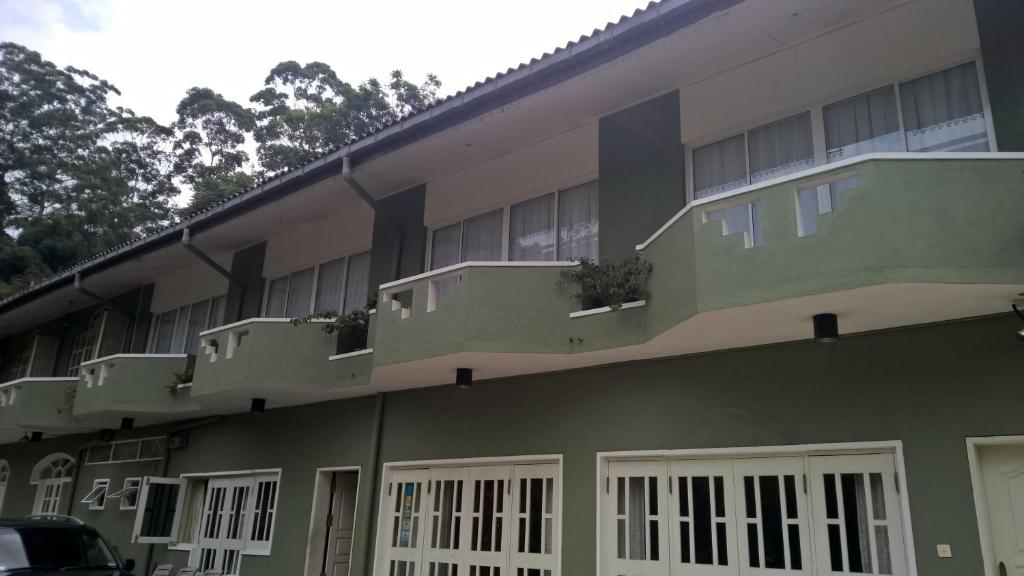 a green building with white windows and a balcony at The Nest by Amarasinghe's in Haputale