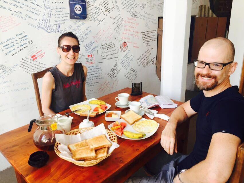 a man and a woman sitting at a table with food at Sanctuary Cove Guest House in Polonnaruwa