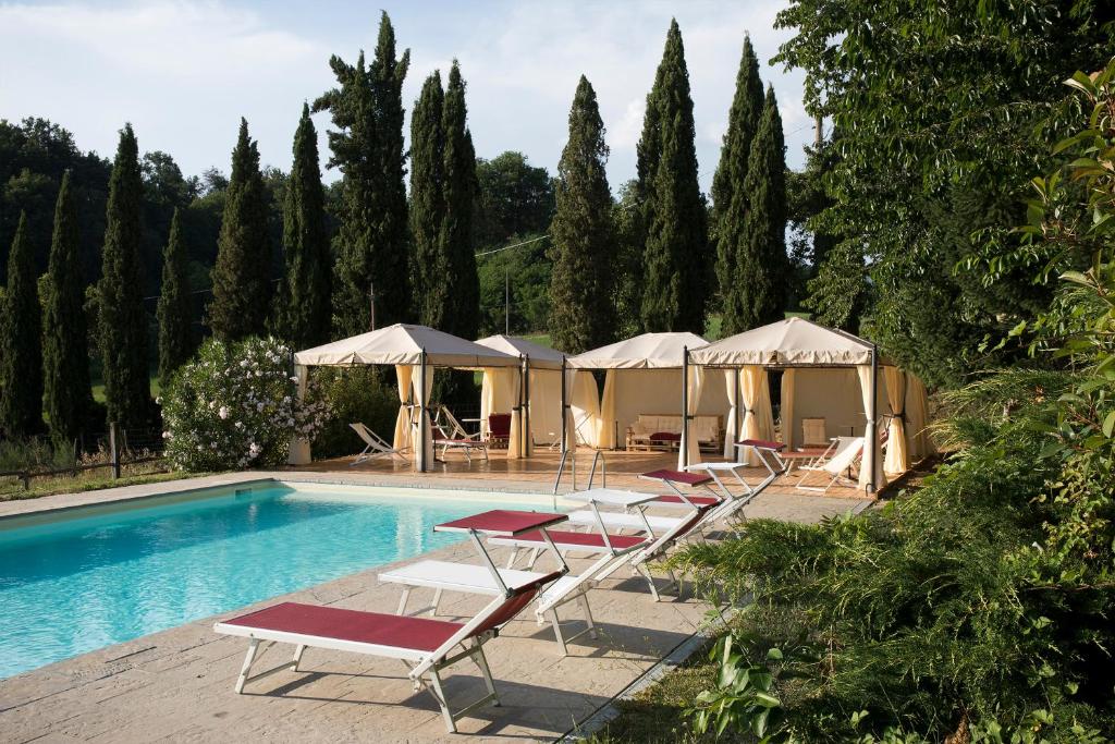 a swimming pool with lounge chairs and umbrellas at Agriturismo La Topaia in Borgo San Lorenzo