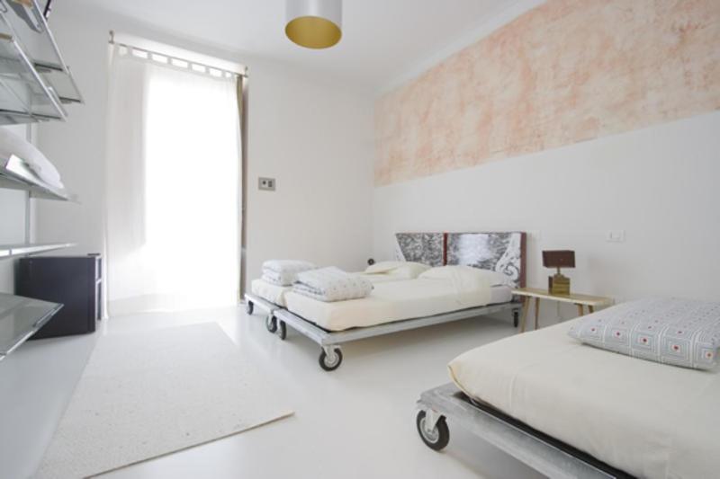 a white bedroom with two beds and a window at A Casa Di Penelope in Rome