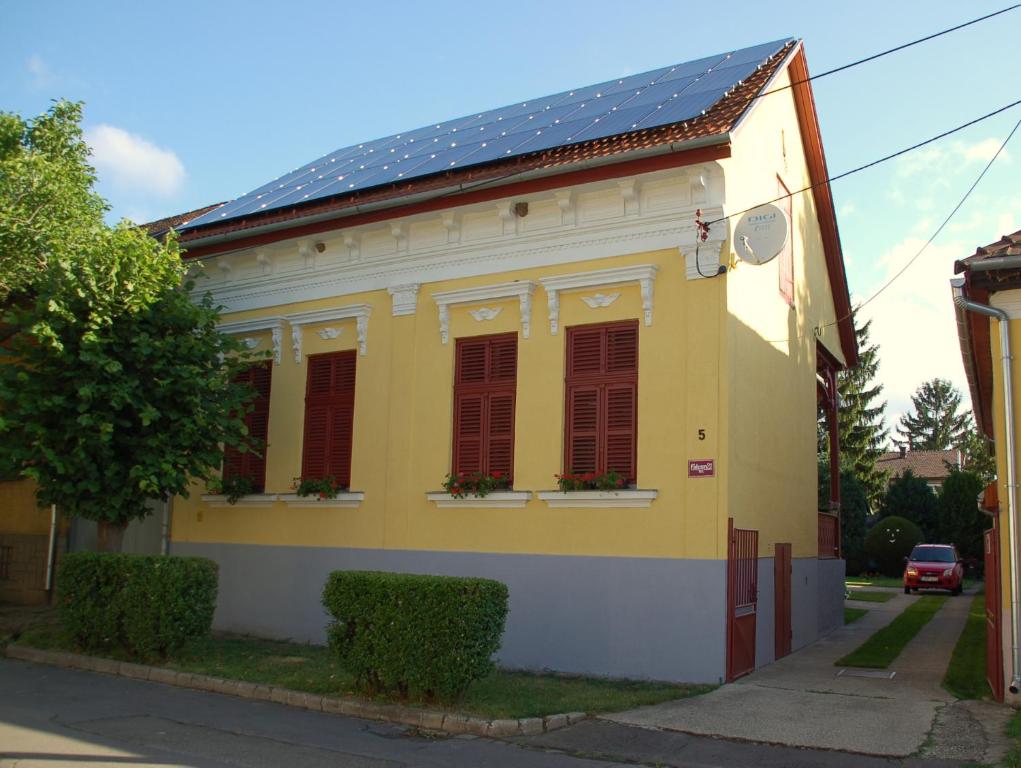 a yellow house with a solar roof on a street at Jakus Ház in Nagymaros