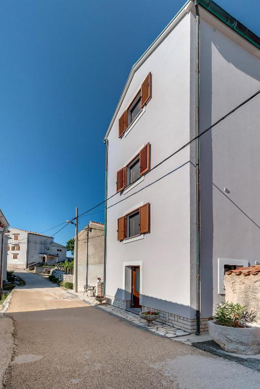 a white building with brown windows on a street at Apartmani Mužić in Orlec