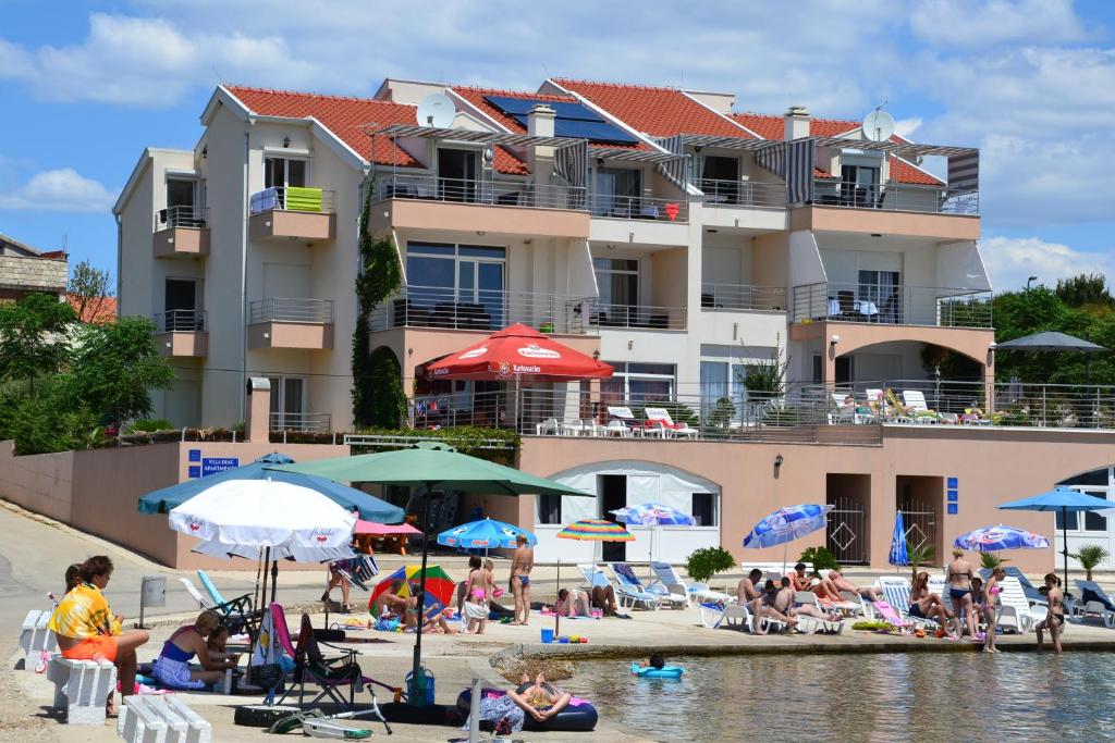 un groupe de personnes sur une plage avec parasols dans l'établissement Apartments Deak, à Janjina