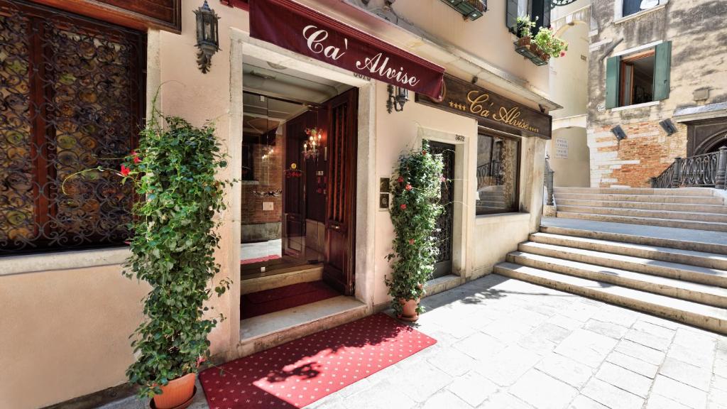 ein Geschäft vor einem Gebäude mit einer roten Matte davor in der Unterkunft Hotel Ca' Alvise in Venedig