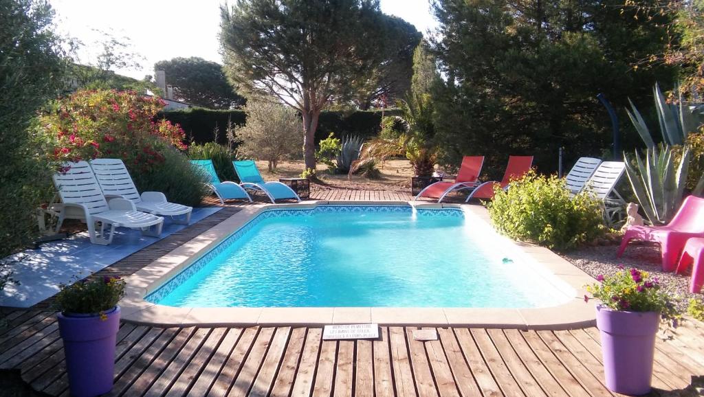 une piscine sur une terrasse en bois avec des chaises autour dans l'établissement La Lucques Masabelle, à Mirepeisset