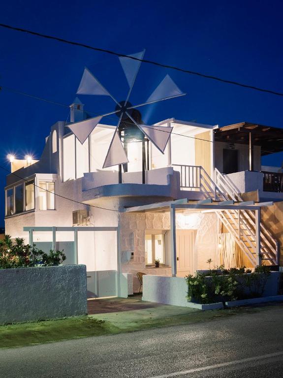 a white house with a windmill at night at Papikinou Bay Suites in Adamantas