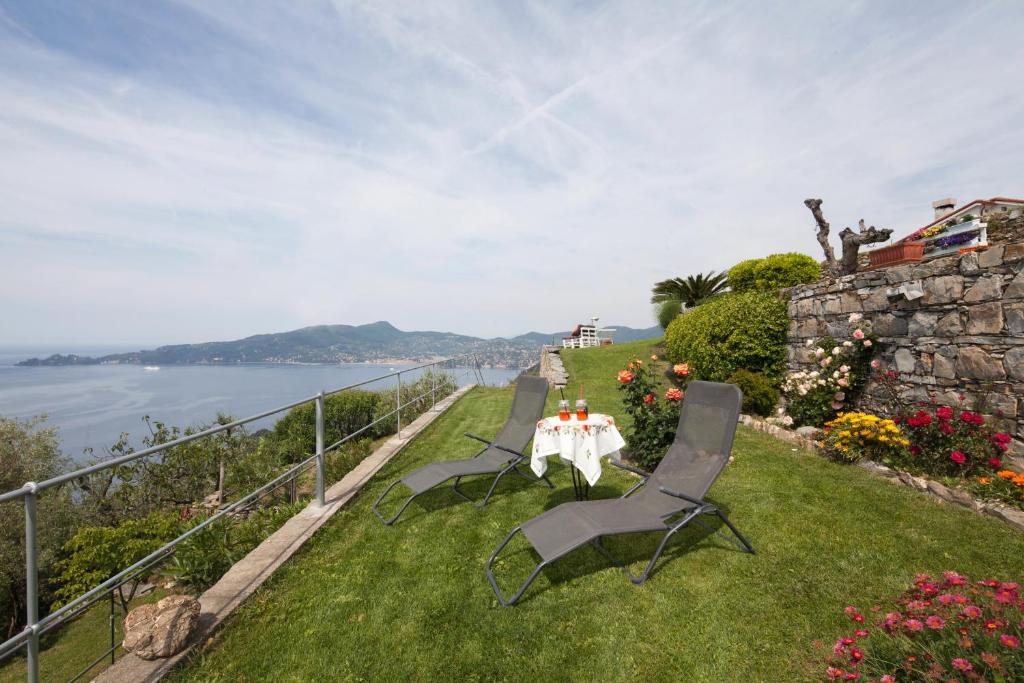 a table and chairs sitting on the grass near the water at Rosso su Portofino in Chiavari