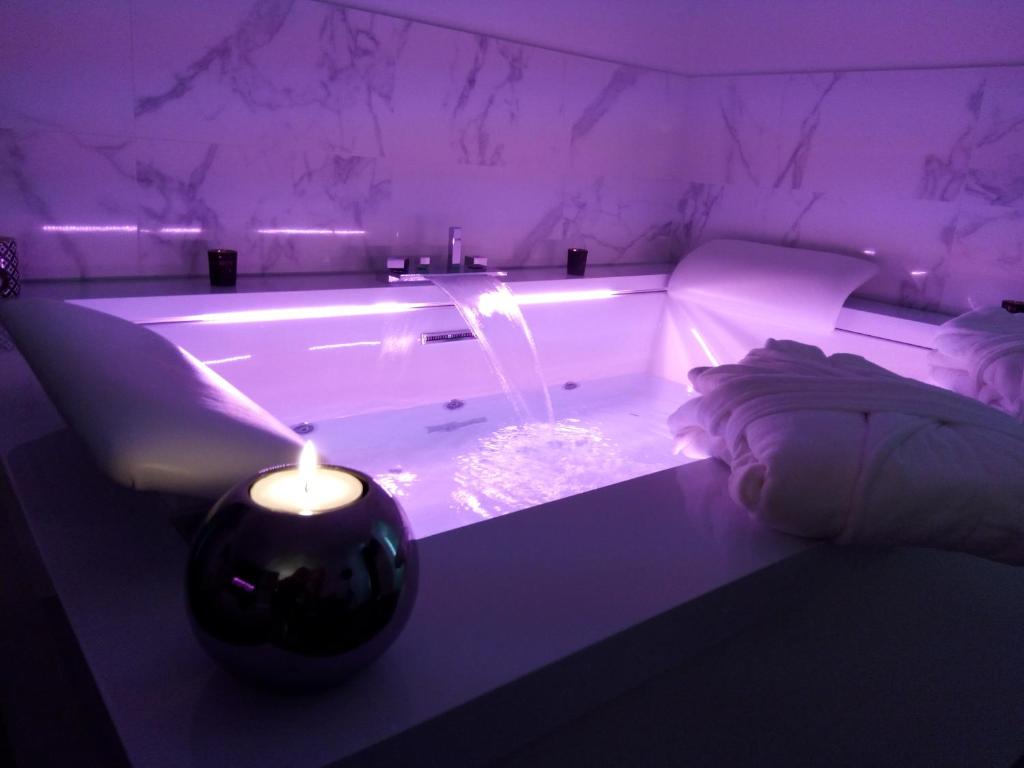- une baignoire avec bougie dans une chambre violette dans l'établissement La Pause Romantique, à Dole