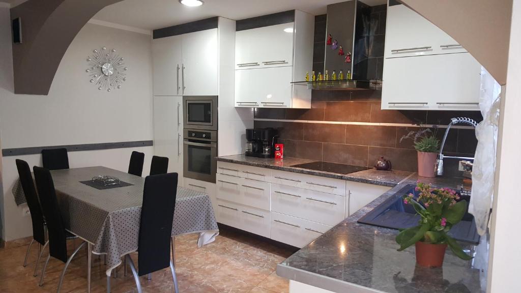 - une cuisine avec des placards blancs et une table à manger dans l'établissement Appartement Carnus Rodez, à Rodez