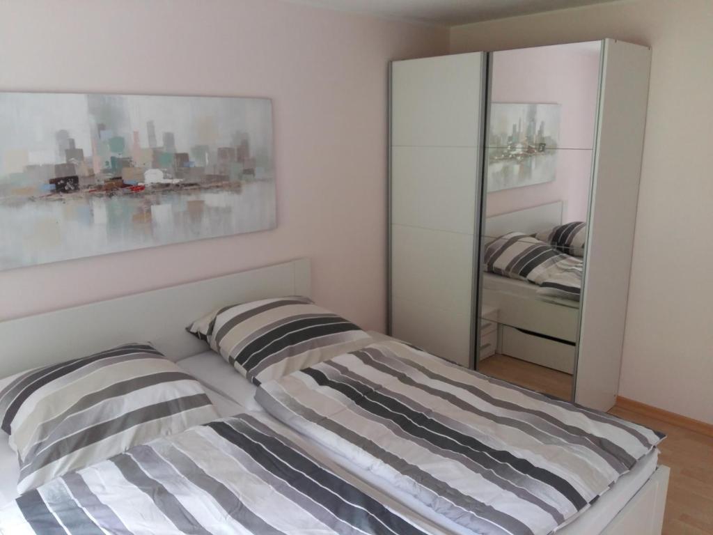 un letto con cuscini a righe in una stanza con specchio di Ferienwohnung Peter Hofling a Wertheim