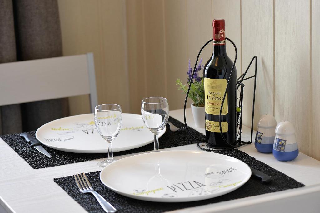 una mesa con dos platos blancos y una botella de vino en Studio "Les pieds dans l'eau" - 50m Front de Mer, en Berck-sur-Mer