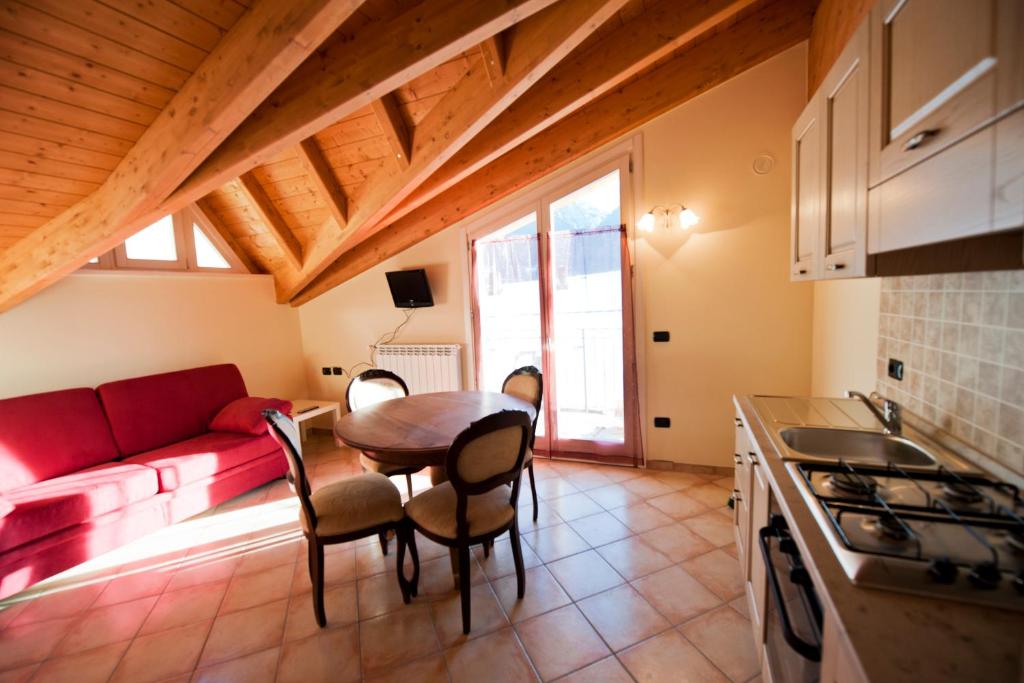 a kitchen and living room with a table and a couch at Residence La Corte in Vezza dʼOglio