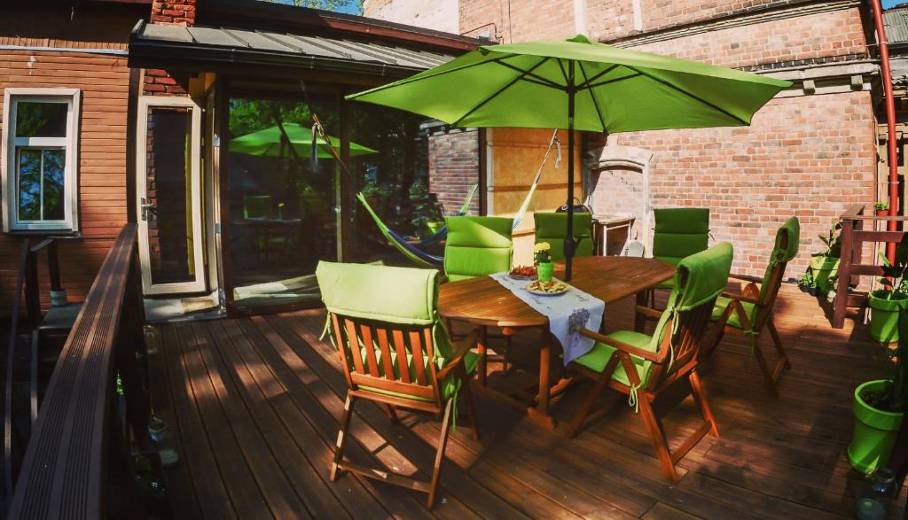 a wooden table and chairs with a green umbrella on a deck at Holiday apartment with terrace in Liepāja