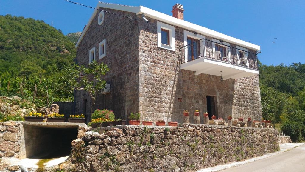 un bâtiment en pierre avec un balcon au-dessus d'un mur en pierre dans l'établissement Apartment Mond, à Virpazar