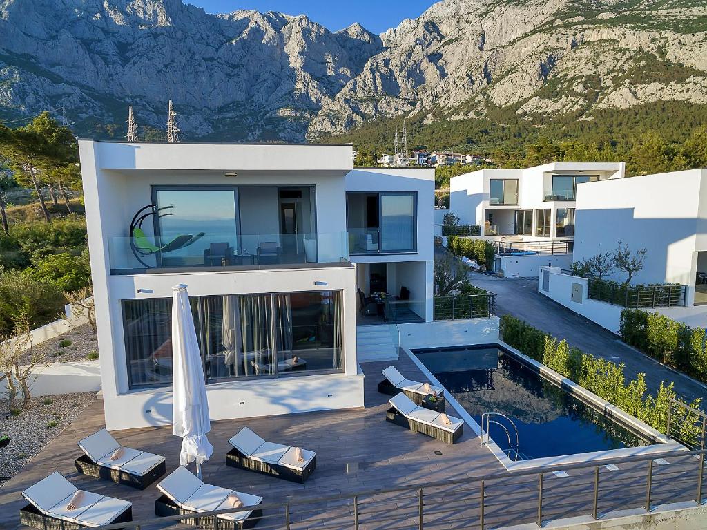 ein Haus mit einer Terrasse mit Stühlen und einem Pool in der Unterkunft Villa Selina - Nera in Makarska