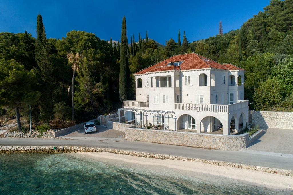 una gran casa blanca en una colina junto al agua en Apartments Villa D&D, en Slano