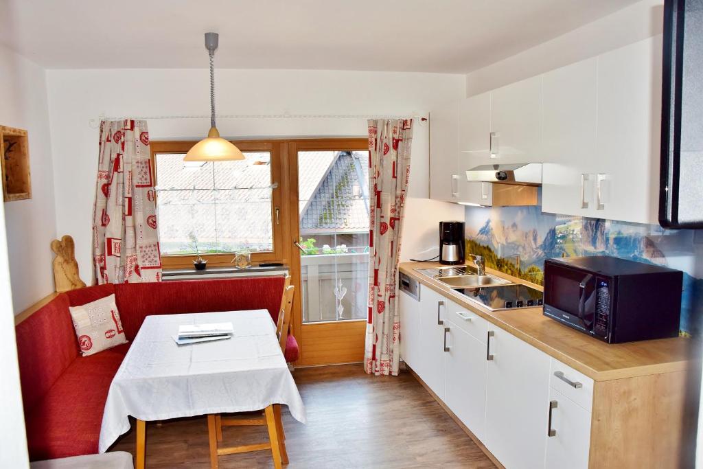 una pequeña cocina con sofá rojo y mesa en Astoria Appartements, en Oberau