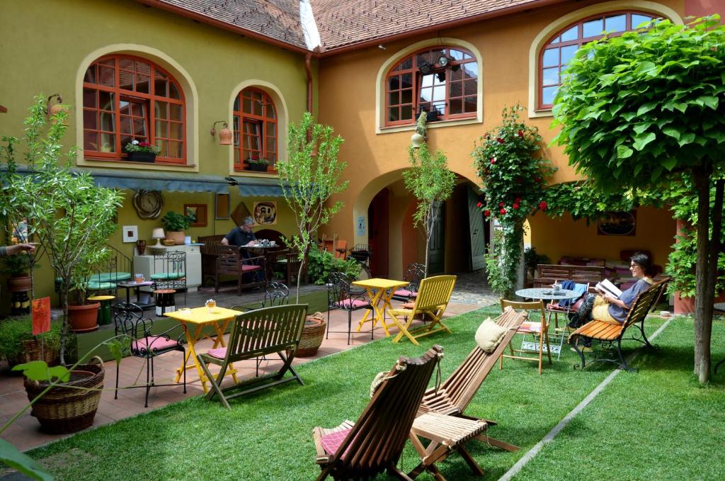 a garden with chairs and tables and people sitting at tables at MuziKafe - Home of Culture in Ptuj
