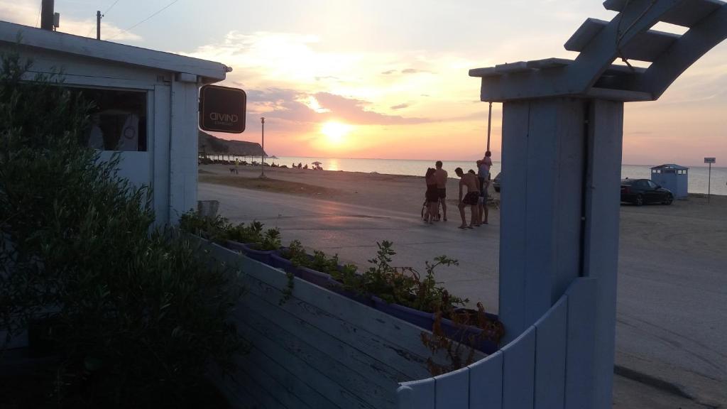 a sunset at the beach with people walking on the beach at Hotel Almira in Agia Triada