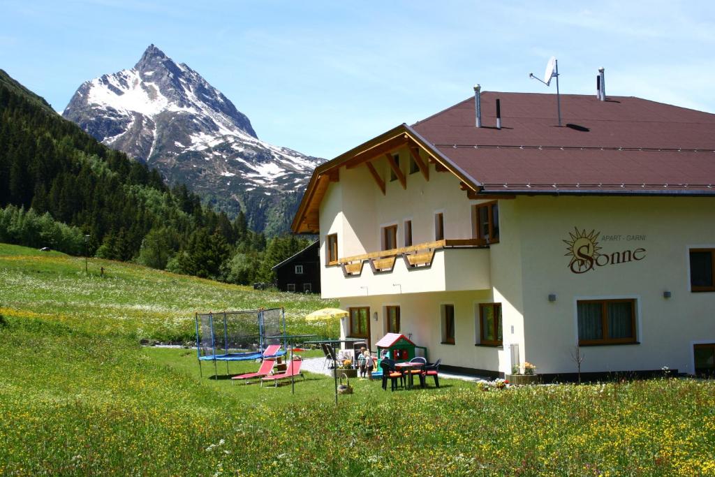 una casa en un campo con una montaña en el fondo en Apart Garni Sonne en Galtür