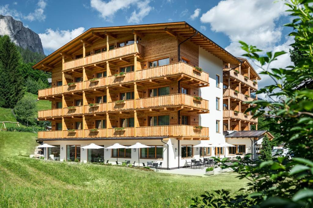 ein großes Gebäude mit Holzbalkonen auf einem Hügel in der Unterkunft Hotel Miramonti in Abtei