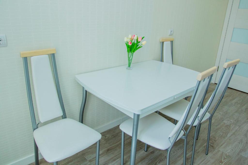 a table and two chairs with a vase of flowers on it at Apartments Manghilik El 53/66 in Astana