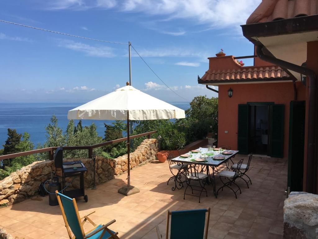 patio con tavolo, sedie e ombrellone di Casa Azzurra a Porto Santo Stefano