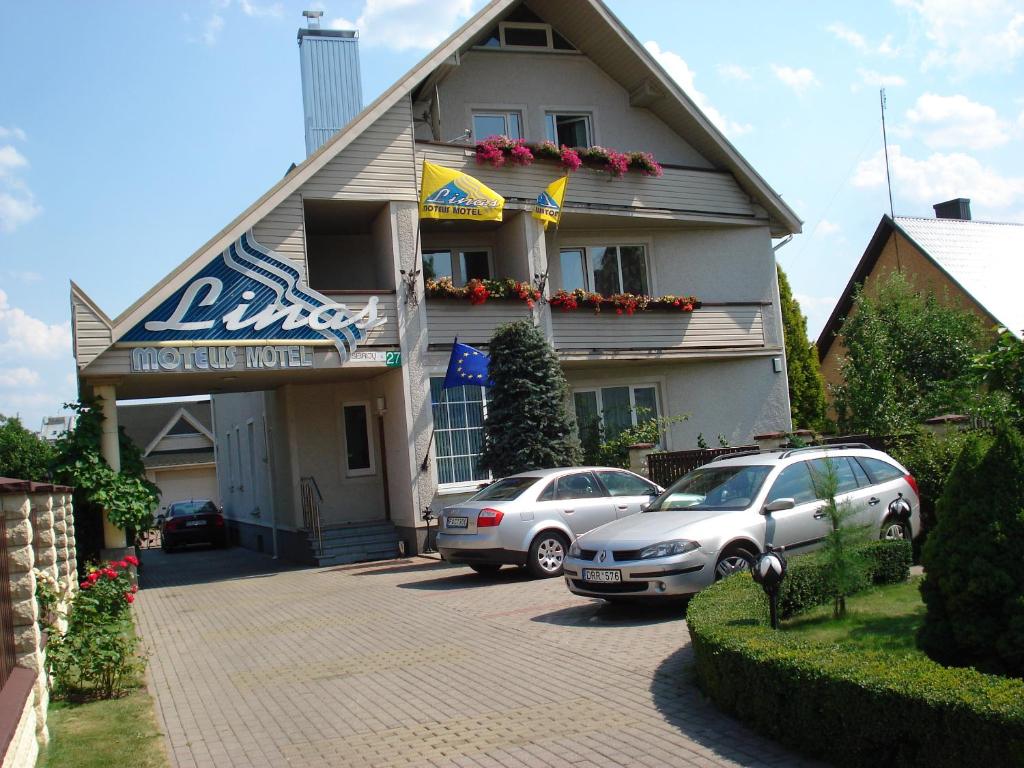 dos coches estacionados frente a un hotel en Guest House Linas, en Alytus