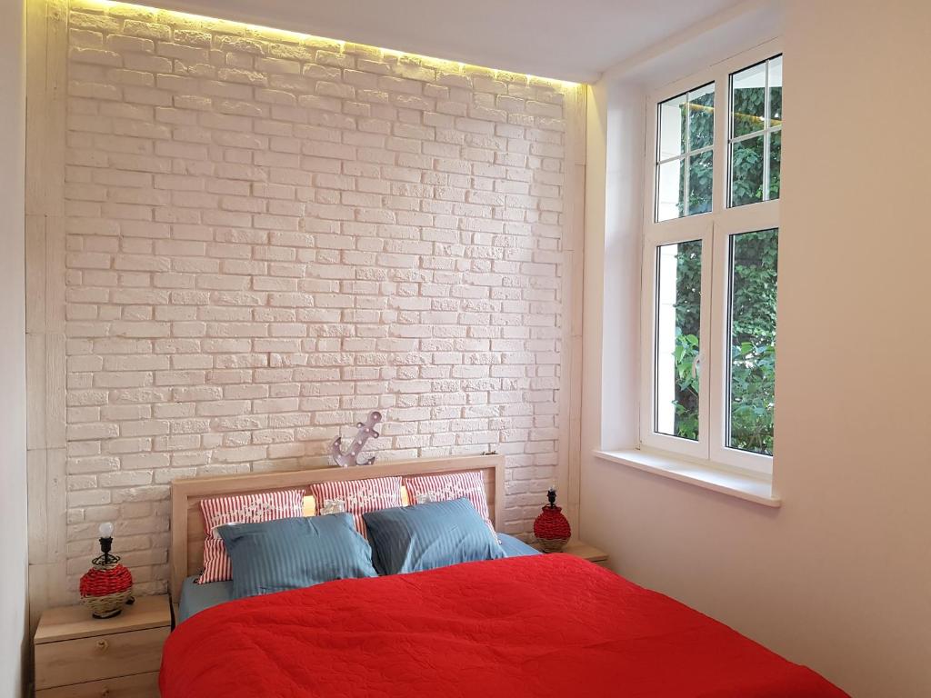 ソポトにあるHouseboat Apartmentの赤いベッドとレンガの壁が備わるベッドルーム1室が備わります。