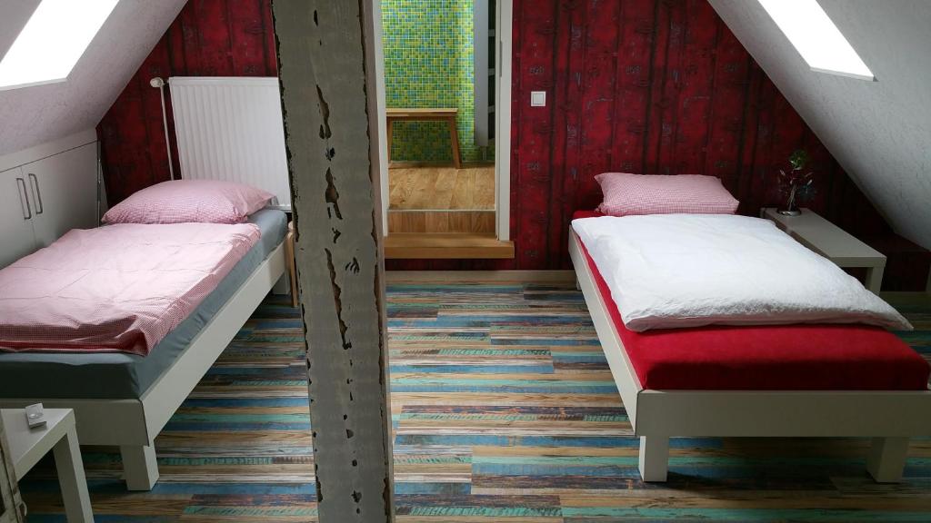 2 Betten in einem Zimmer mit roten Wänden in der Unterkunft Ferienwohnungen Abraham in Nienhagen