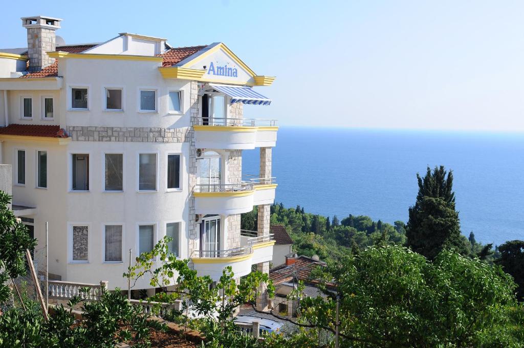 a white building on a hill next to the ocean at Apartments Amina in Ulcinj