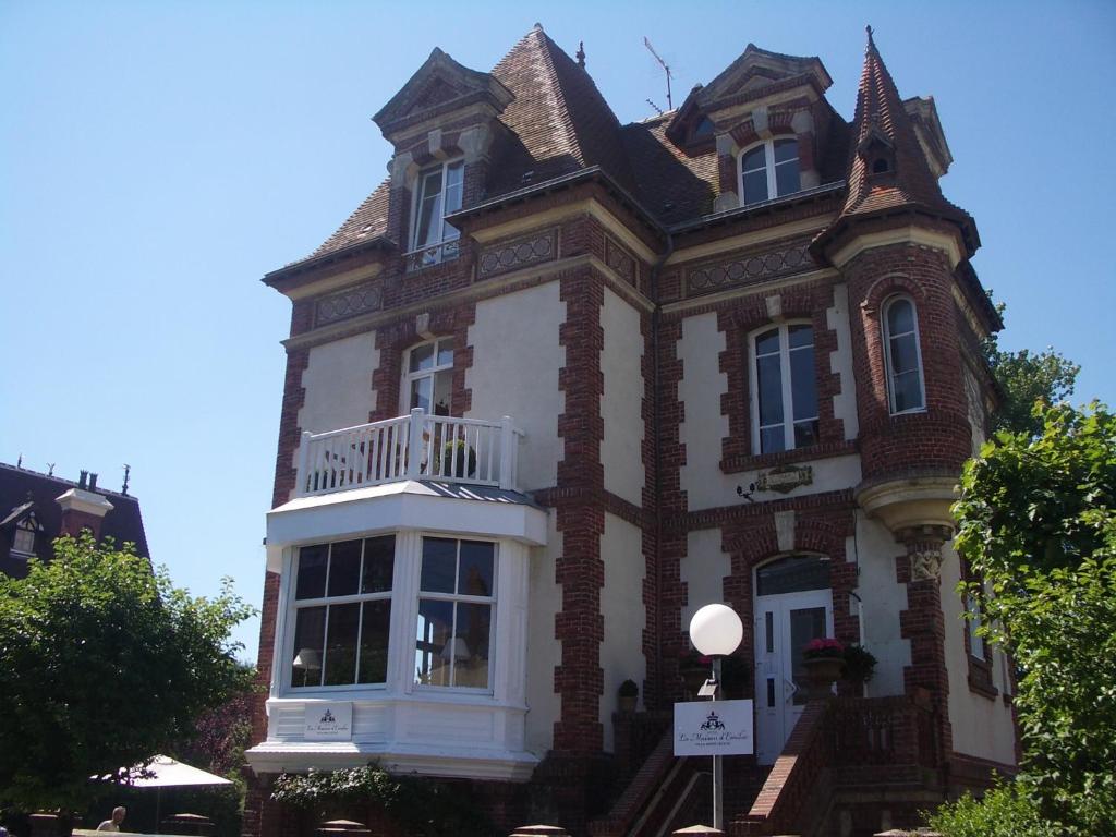 duży ceglany budynek z balkonem w obiekcie La Maison d'Emilie w mieście Houlgate