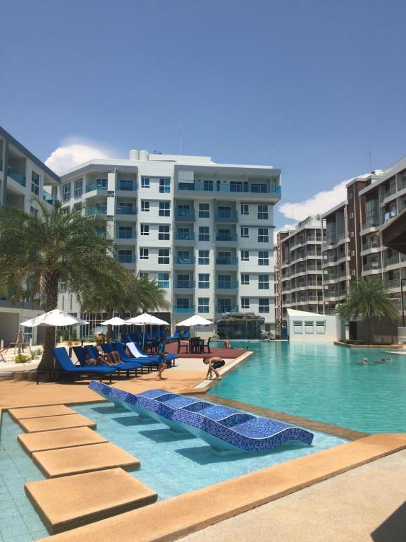 una grande piscina con sedie blu e edifici di Grand Blue Condominium by Nuttaya a Klaeng