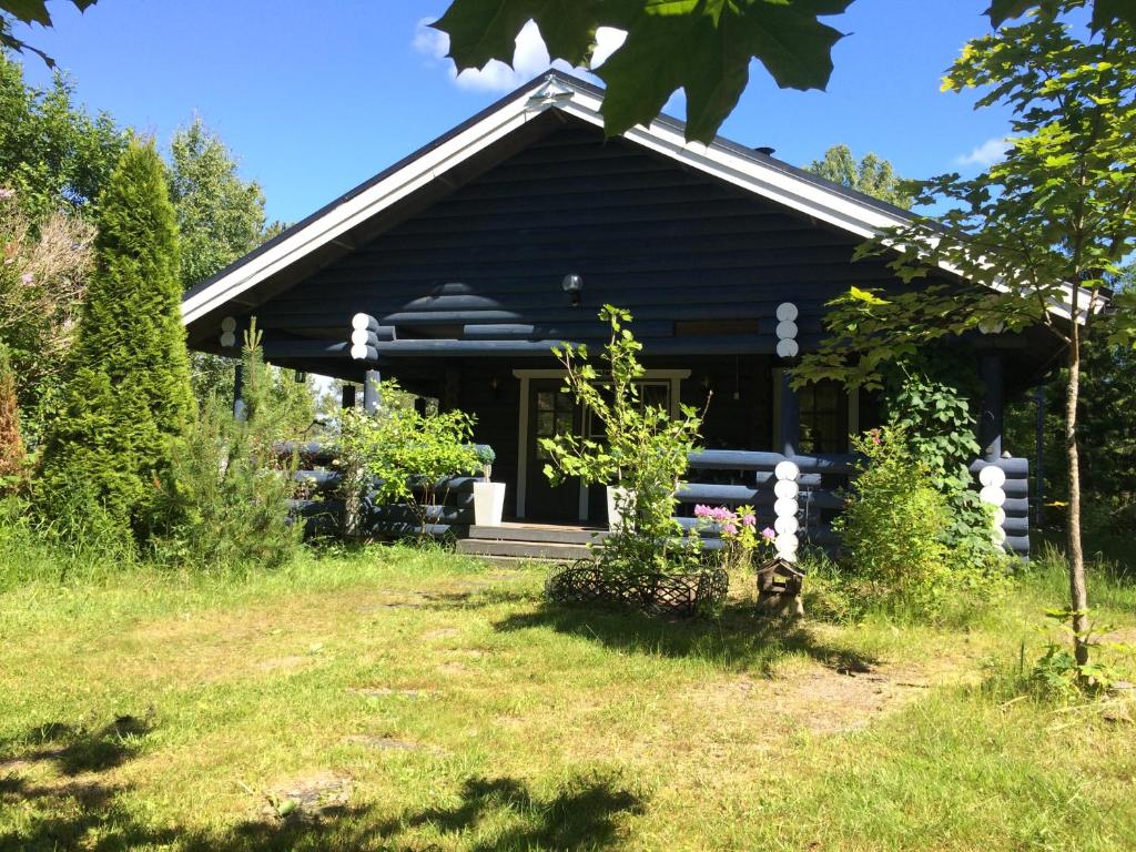 a black house with a yard in front of it at Kallioranta Cottage in Ruokolahti