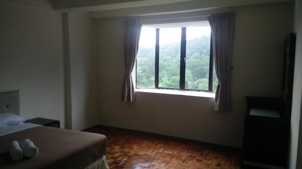 a bedroom with a bed and a large window at Lumut Valley Resort Condominium in Lumut