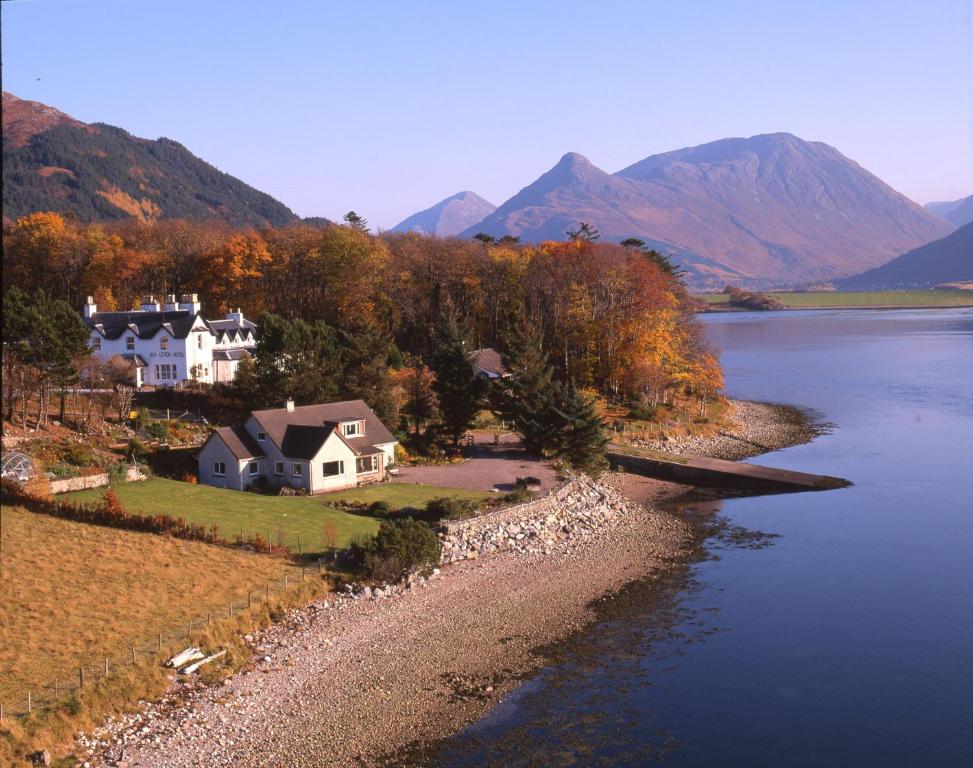 a house on a hill next to a body of water at Loch Leven Hotel & Distillery in Glencoe
