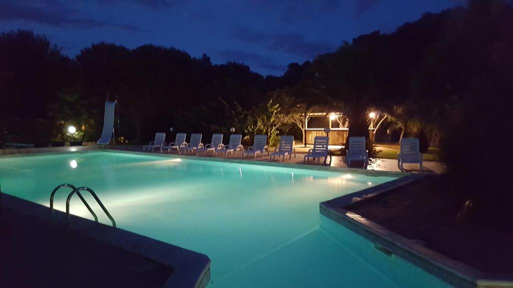 a swimming pool at night with chairs and lights at Hotel La Valle in Carloforte