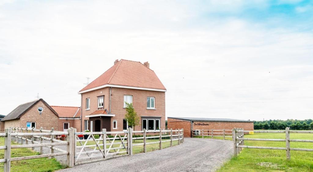a brick house with a fence on a dirt road at De Perenboom in Belsele