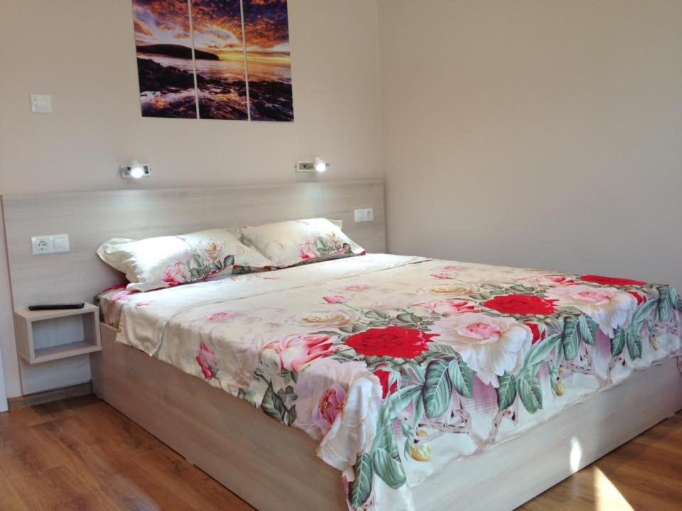 ブルガスにあるBeachfront Sea Garden Apartmentのベッドルーム1室(花柄の掛け布団付きのベッド1台付)