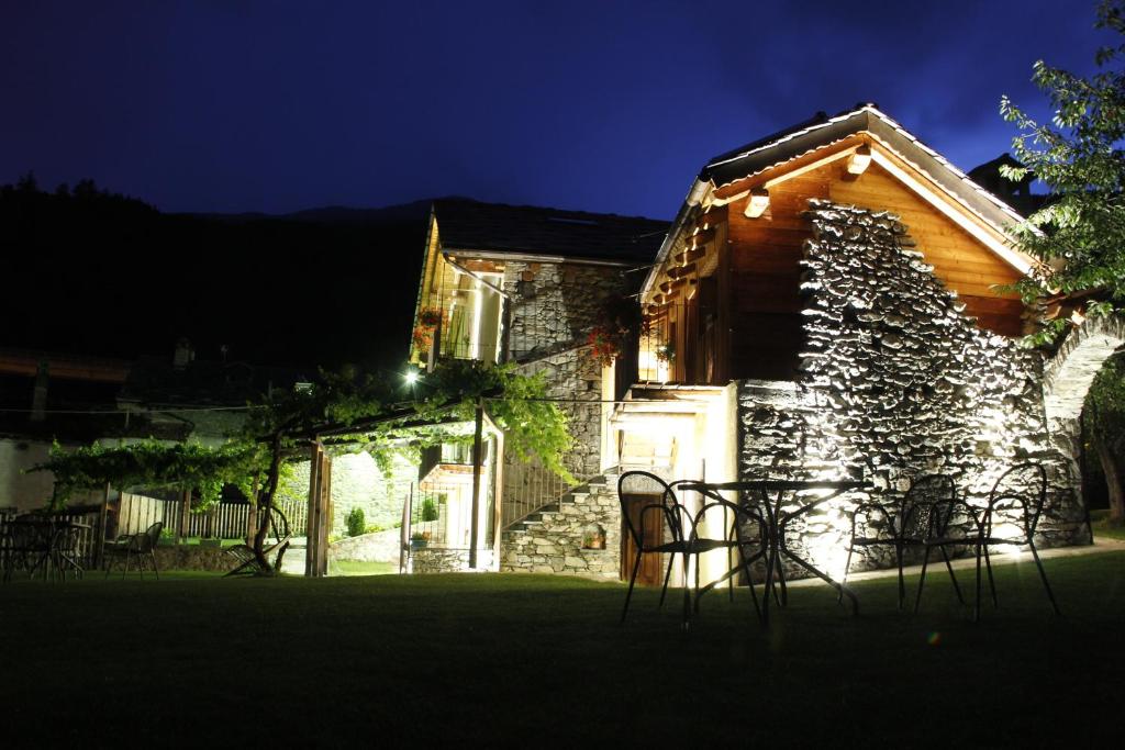 ein Steinhaus mit Stühlen im Hof in der Nacht in der Unterkunft Affittacamere Grand Saint Bernard in Gignod