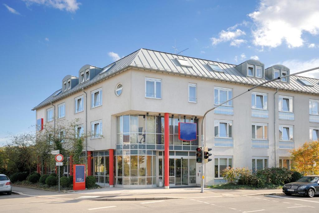 een groot wit gebouw op een straat met een verkeerslicht bij Hotel Stuttgart Sindelfingen City by Tulip Inn in Sindelfingen