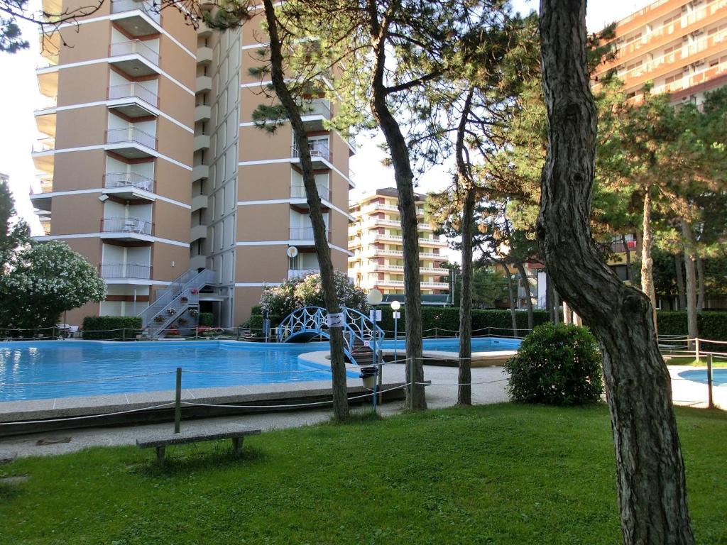 un parc avec un banc en face d'une piscine dans l'établissement Residence Cristallo, à Lignano Sabbiadoro